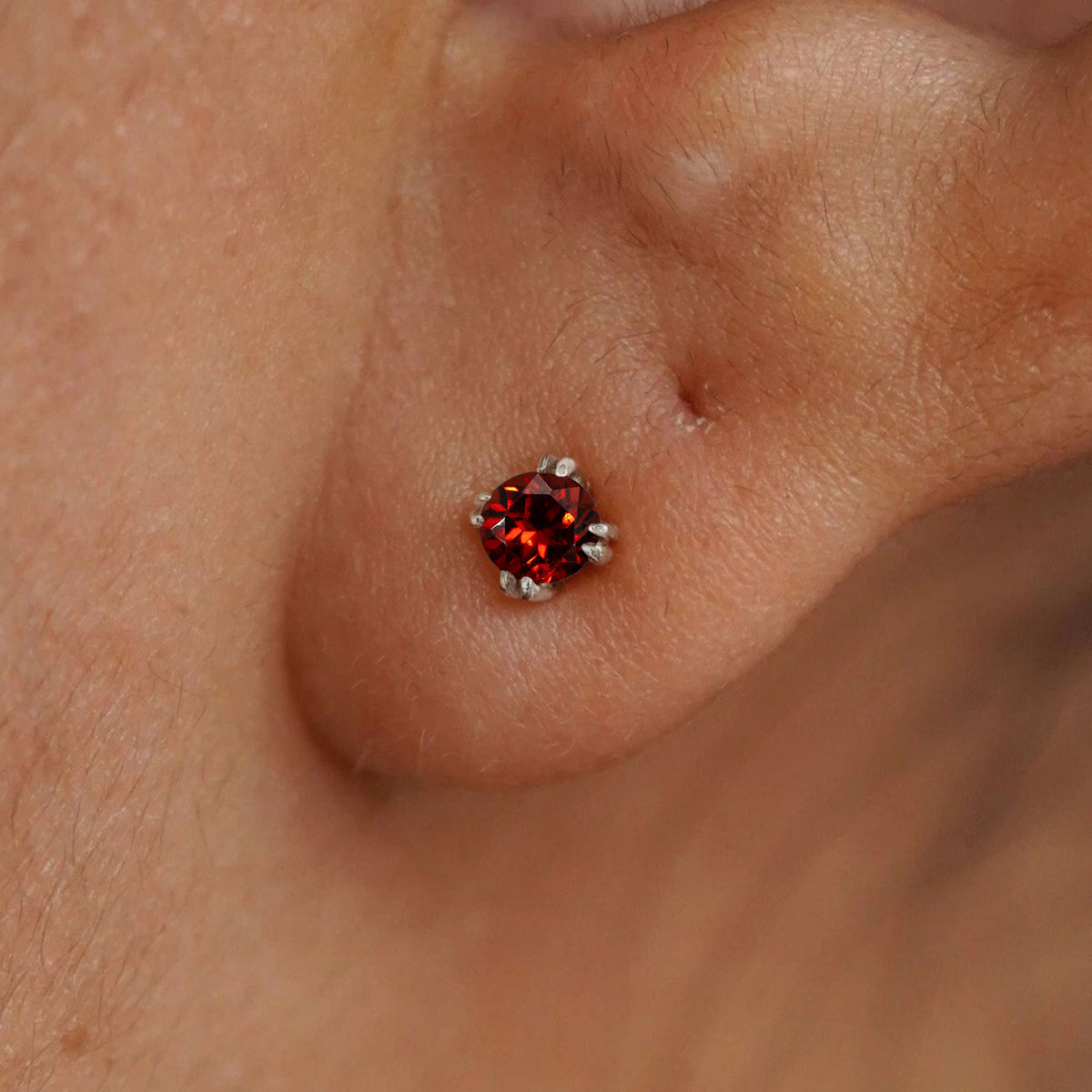 Close up view of a model's ear wearing a 14k white gold Garnet Earring