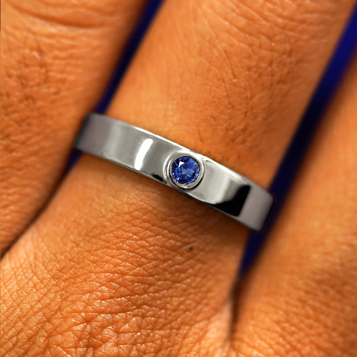 Close up view of a model's fingers wearing a 14k white gold sapphire Gemstone Industrial Band