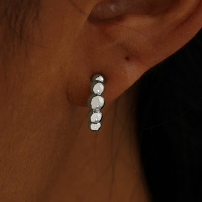 Close up view of a model's ear wearing a 14k white gold Graduated Puffy Beaded Hoop