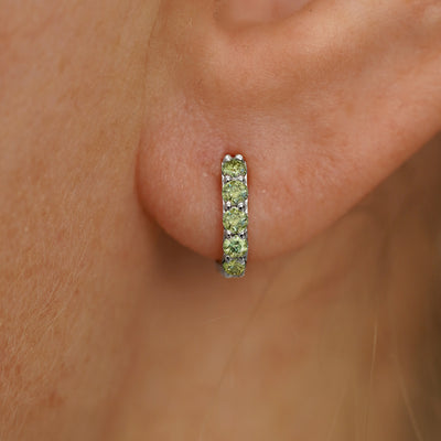 Close up view of a model's ear wearing a white gold Mini Light Green Lab Diamond Huggie Hoop