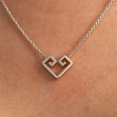 A close up view of a model's neck wearing a white gold Large Chere Heart Necklace