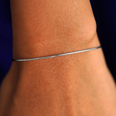 Close up view of a model's wrist wearing a white gold Line Bangle Bracelet