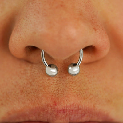 Close up view of a model's nose wearing a 14k white gold Medium Horseshoe in a septum piercing