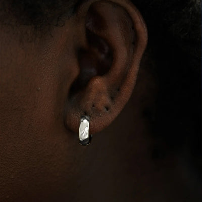 Close up view of a model's ear wearing a 14k white gold Medium Wide Huggie Hoop Earring