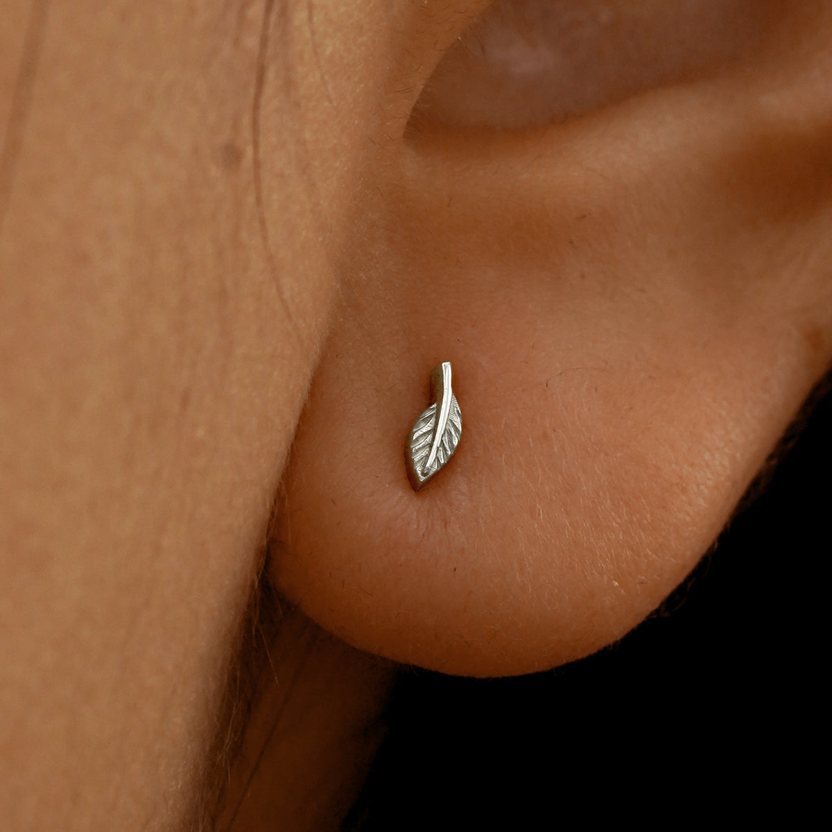 Close up view of a model's ear wearing a 14k white gold Mini Leaf Earring