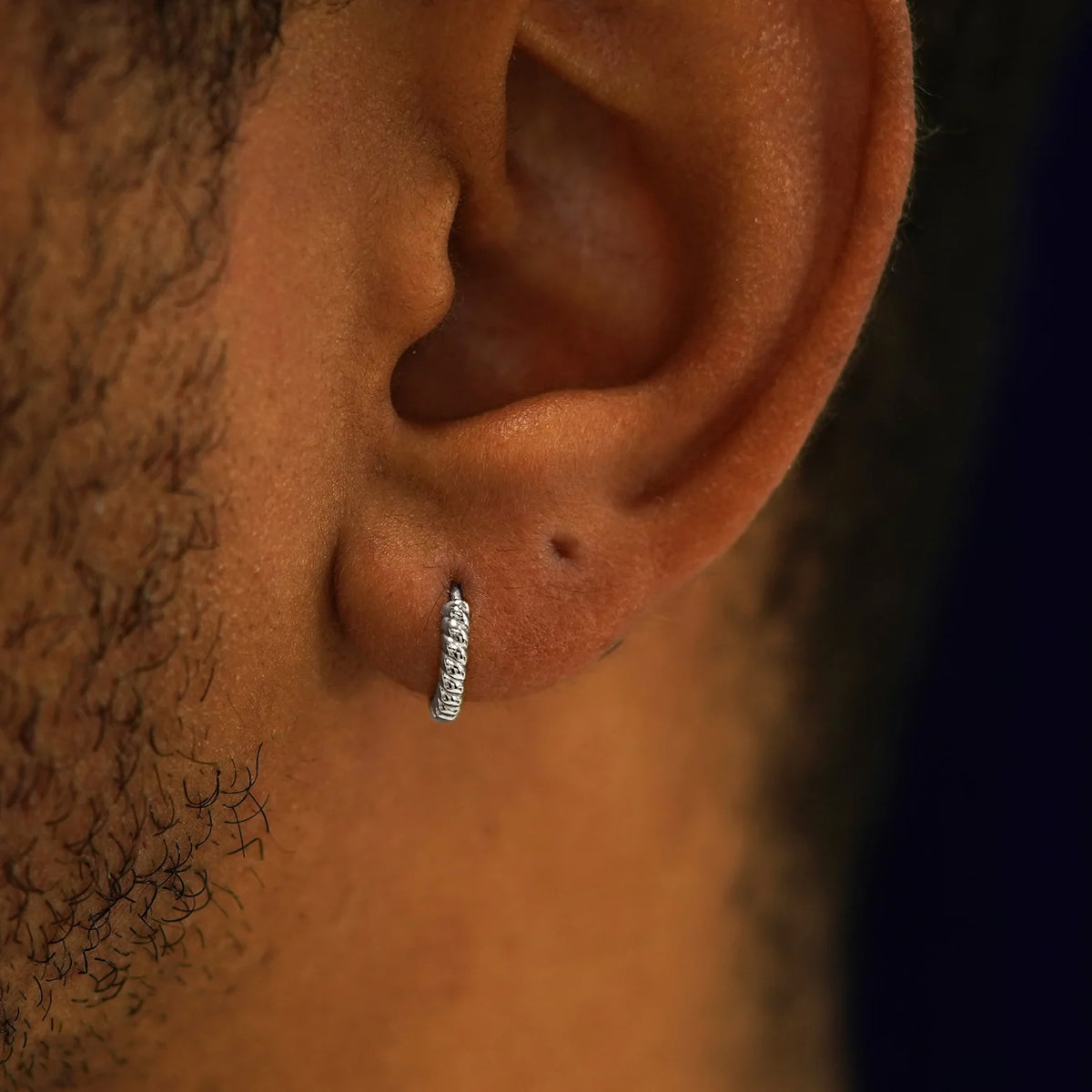 A model's ear wearing a 14k white gold Mini Rope Huggie Hoop Earring