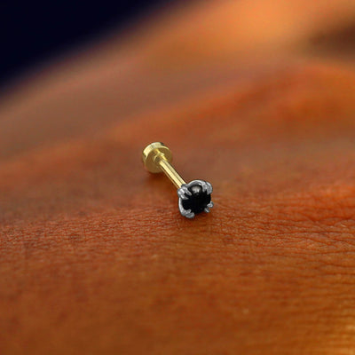 A solid 14k white gold Onyx Flatback Piercing resting on the back of a model's hand