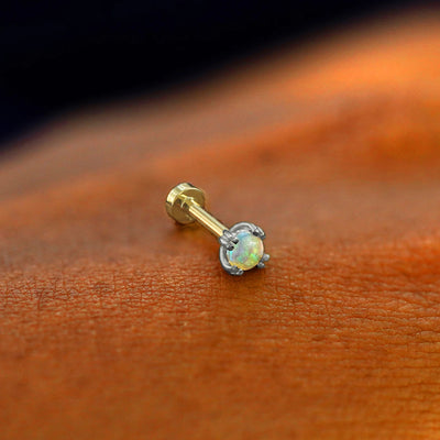 A solid 14k white gold Opal Flatback Piercing resting on the back of a model's hand