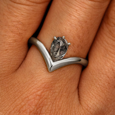 A model's hand wearing a 14k white gold Pear Salt and Pepper Diamond Chevron Ring