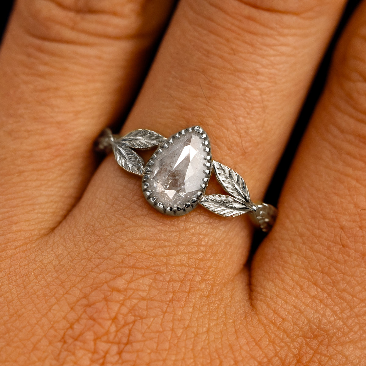 Close up view of a model's fingers wearing a 14k white gold Pear Salt and Pepper Diamond Leaves Ring