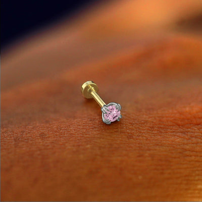 A solid 14k white gold pink sapphire Piercing resting on the back of a model's hand
