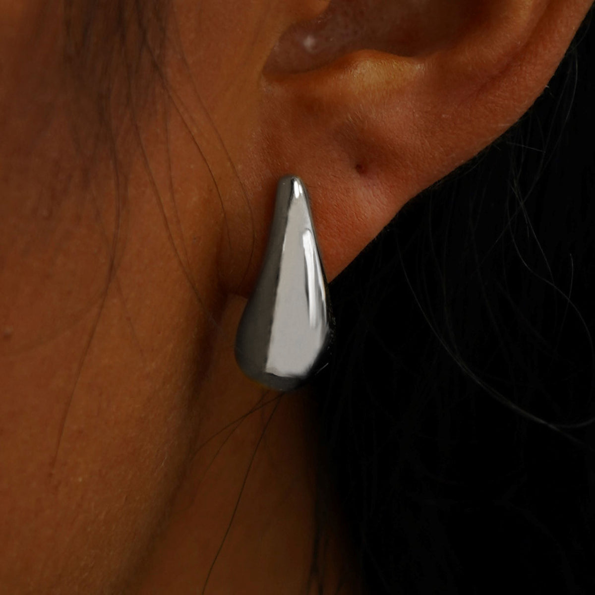 Close up view of a model's ear wearing a white gold black 5mm Moissanite Earring