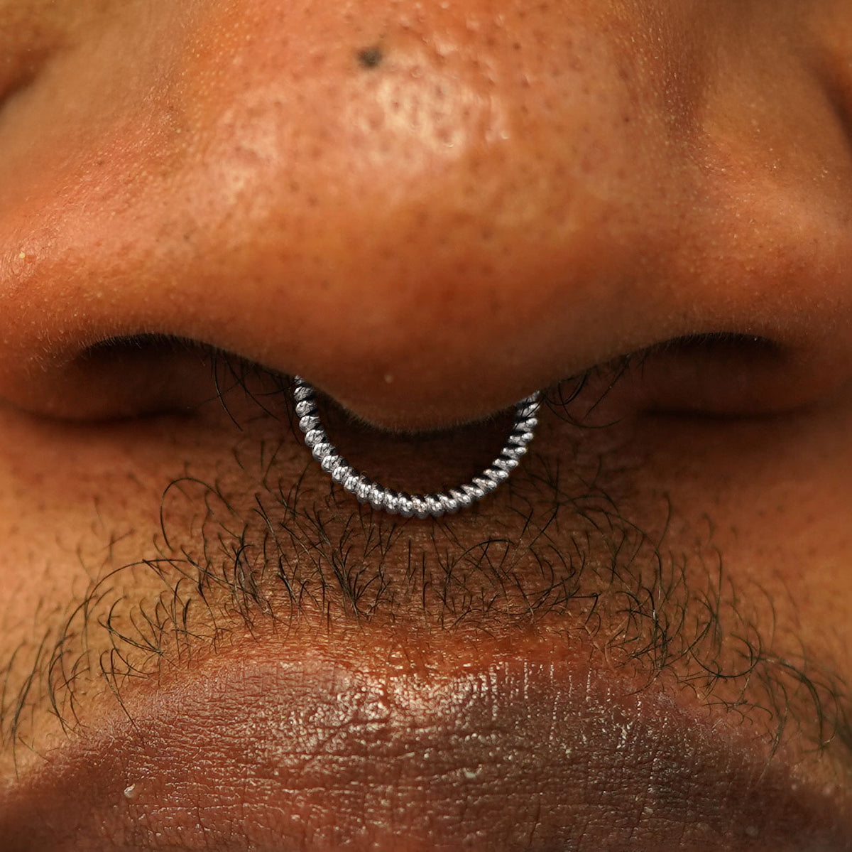 Close up view of a model's nose wearing a 14k white gold Rope Septum