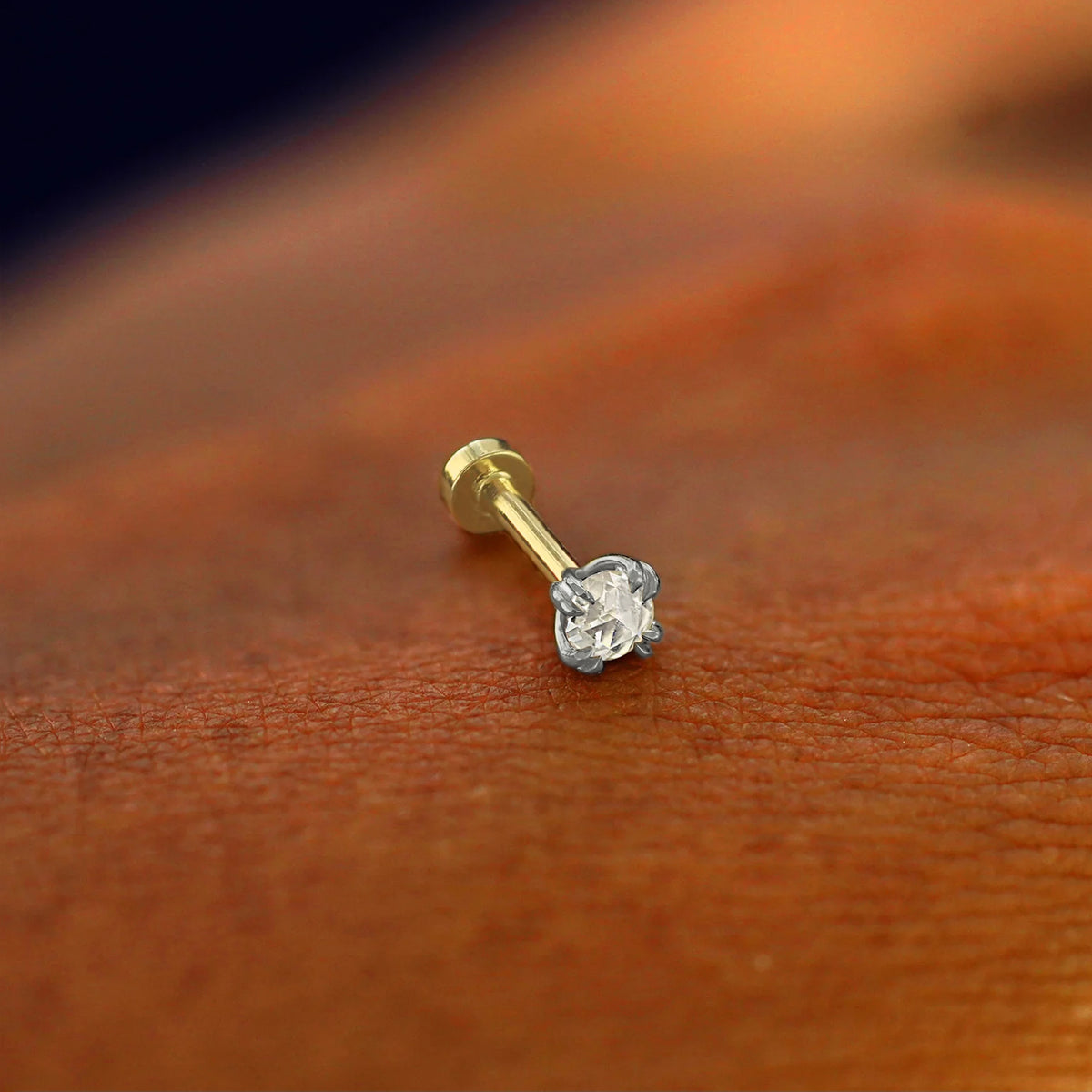 A solid 14k white gold Rose Cut Diamond Flatback Piercing resting on the back of a model's hand