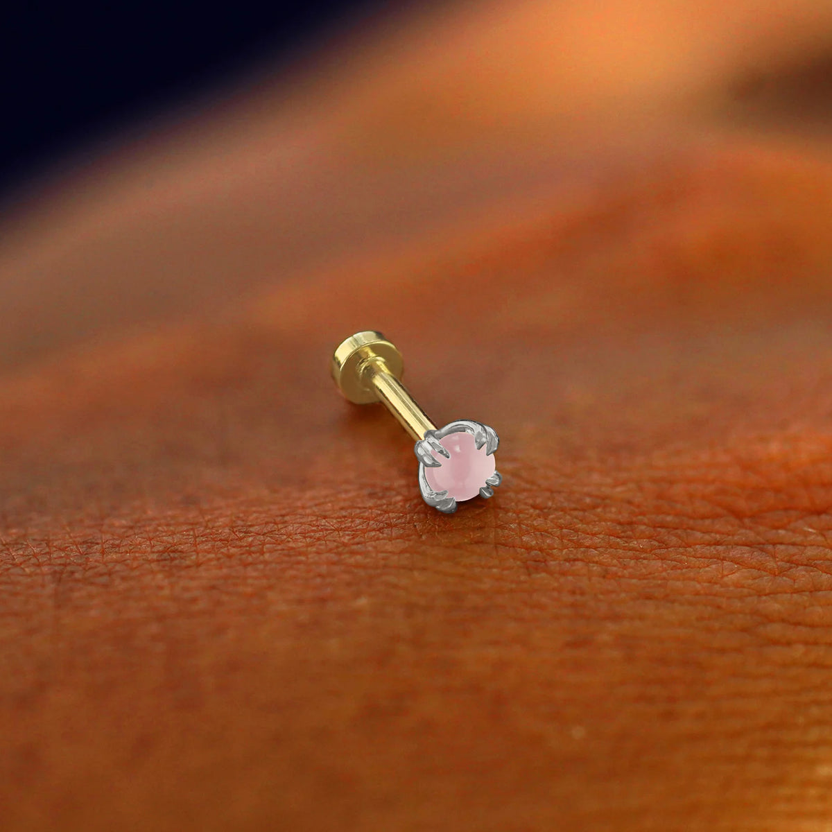A solid 14k white gold Rose Quartz Flatback Piercing resting on the back of a model's hand