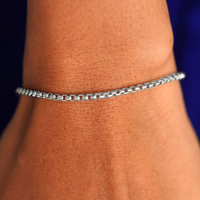 A model's wrist wearing a white gold Round Box Chain Bracelet