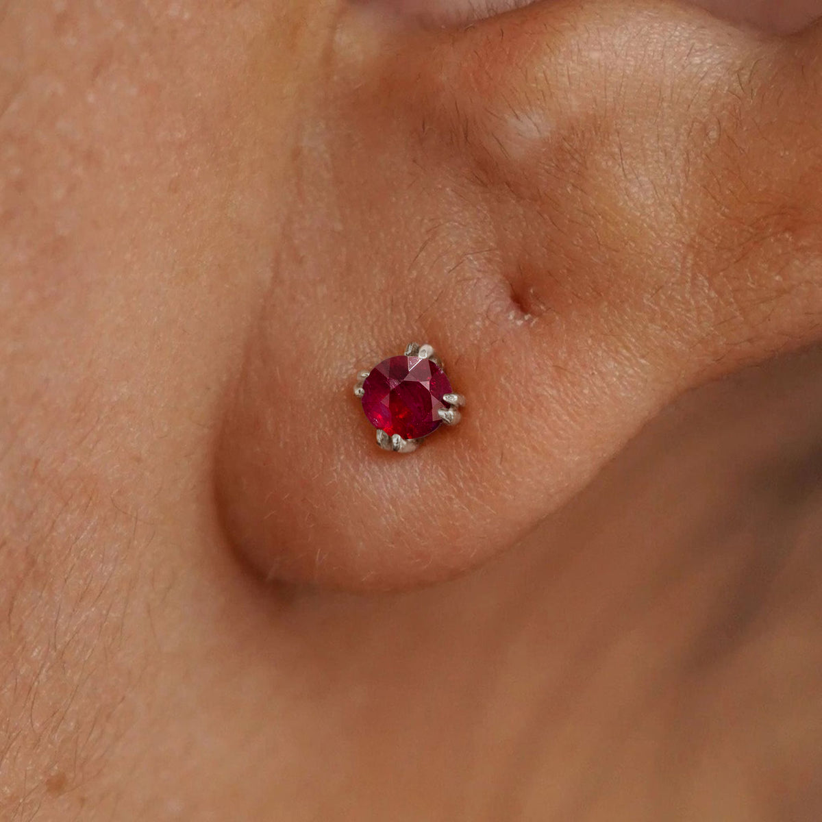 Close up view of a model's ear wearing a 14k white gold Ruby Earring