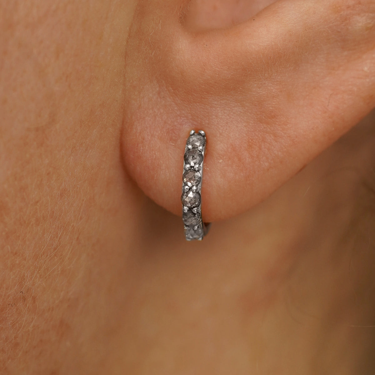 Close up view of a model's ear wearing a white gold Small Salt and Pepper Diamond Huggie Hoop