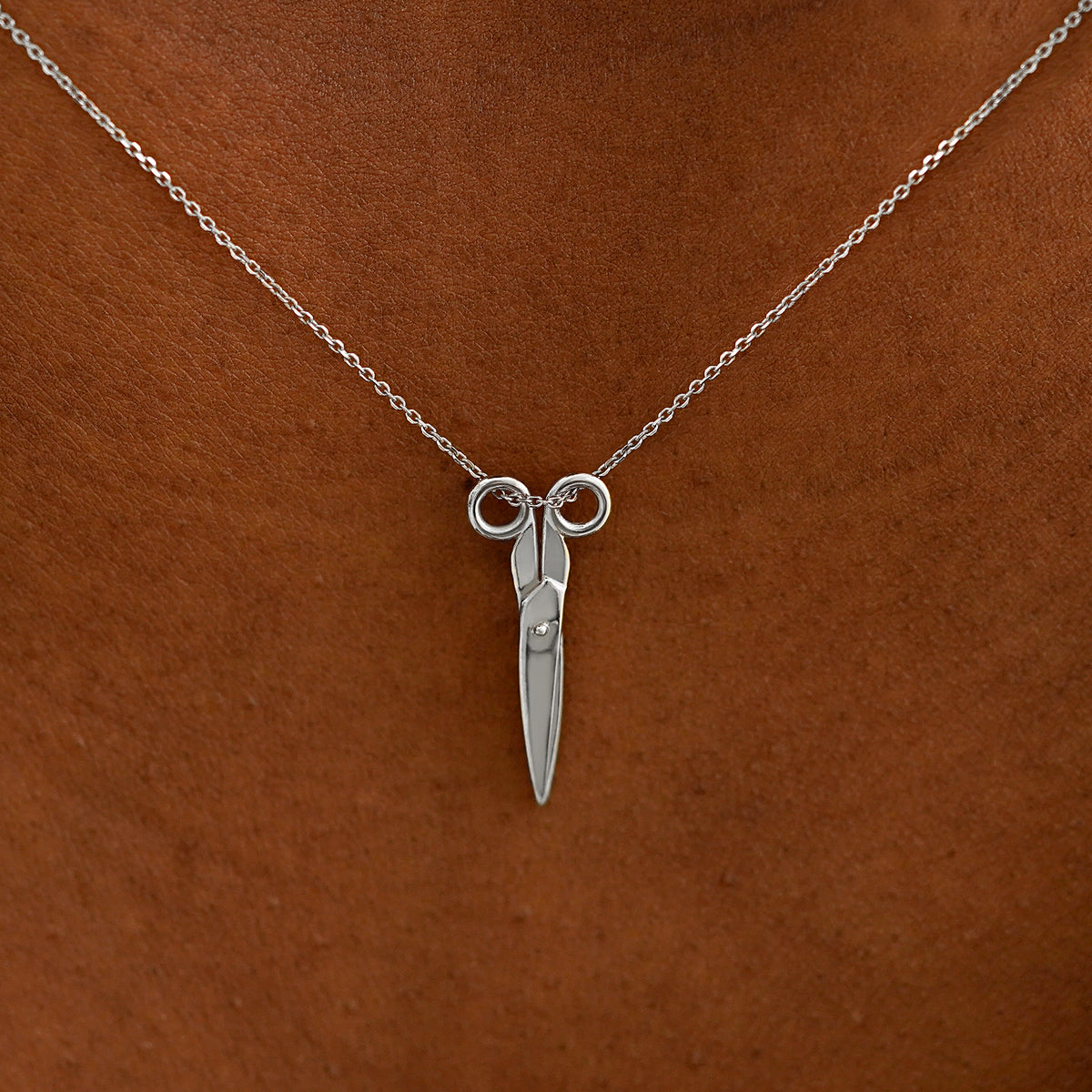 Close up view of a model's neck wearing a solid 14k white gold Scissors Necklace