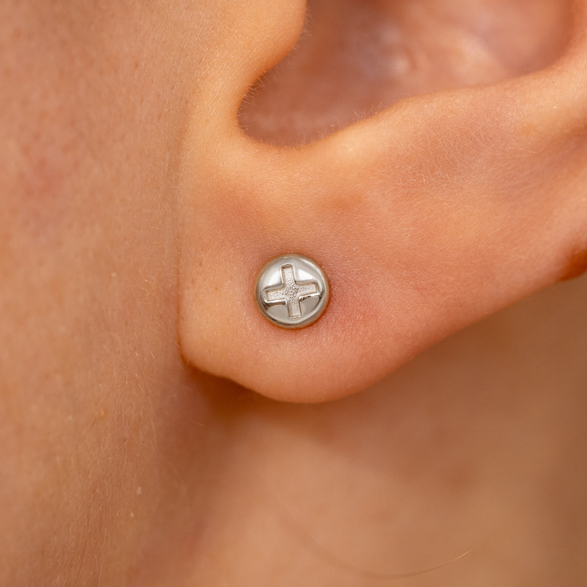 Close up view of a model's ear wearing a white gold Screw Earring