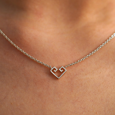A close up view of a model's neck wearing a white gold Small Chere Heart Necklace
