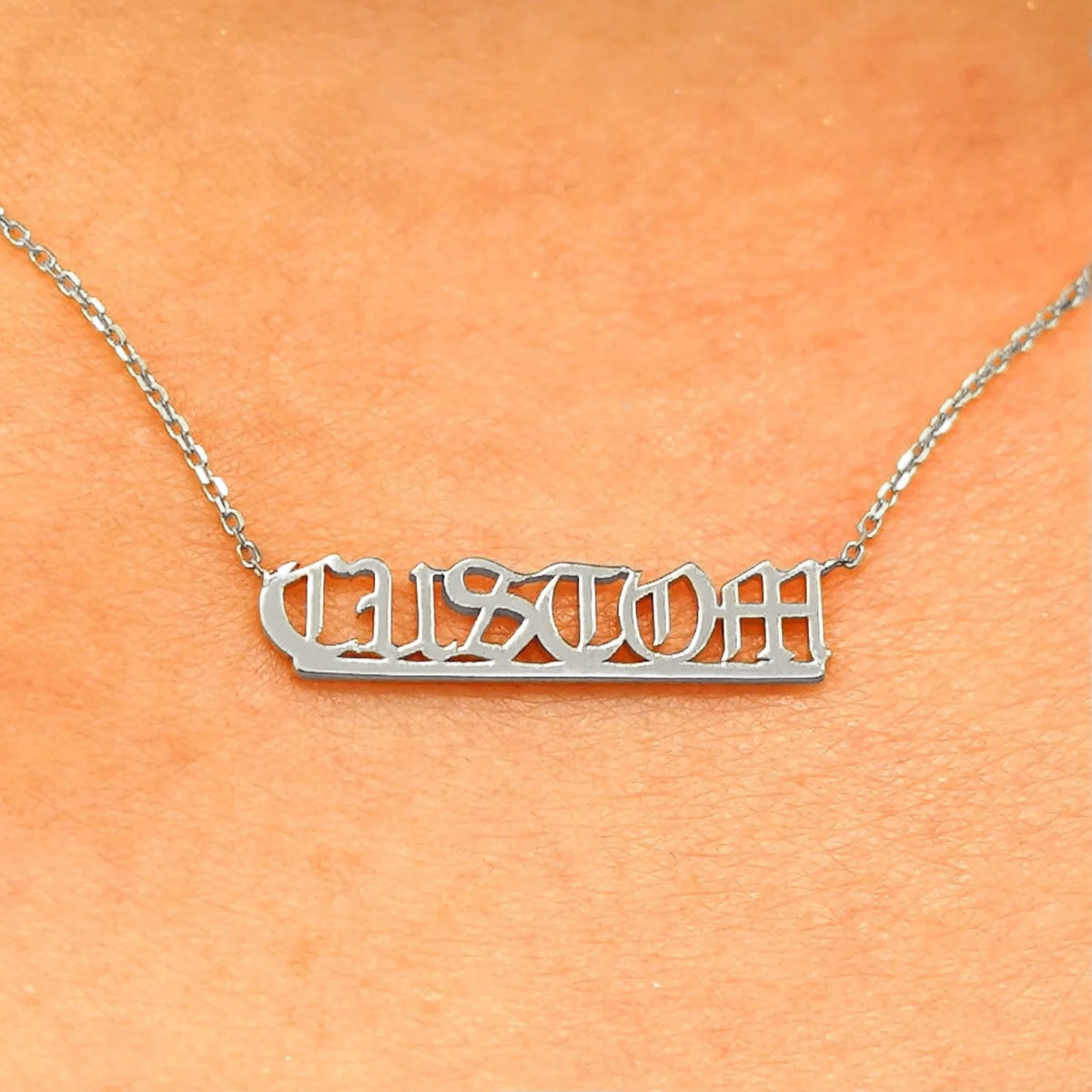 Close up view of a model's neck wearing a white gold Small Custom Nameplate necklace that says Custom