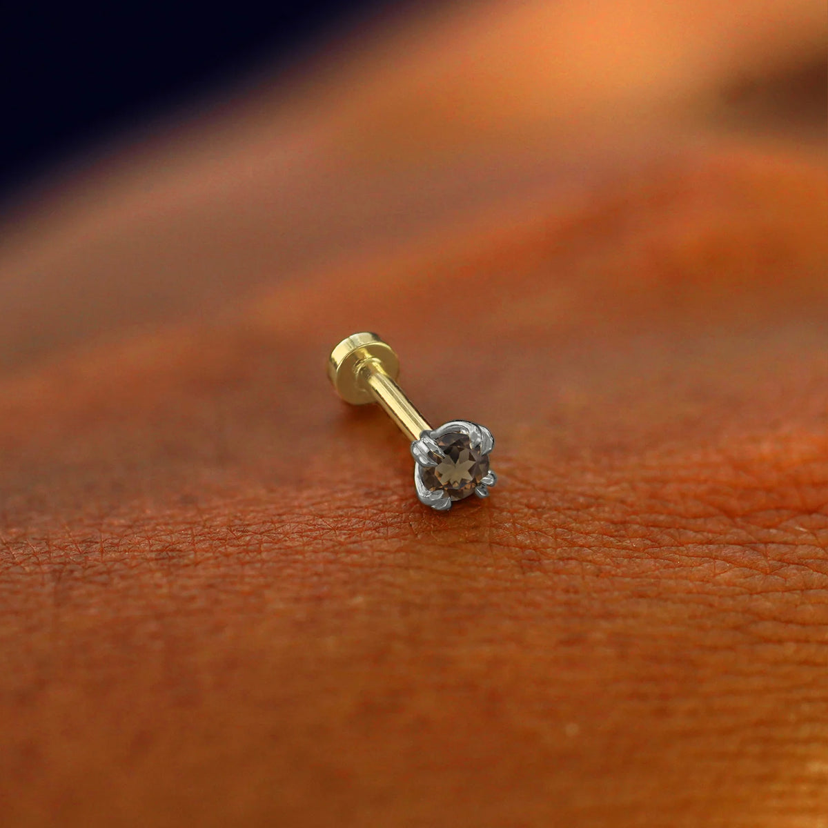A solid 14k white gold Smoky Quartz Flatback Piercing resting on the back of a model's hand