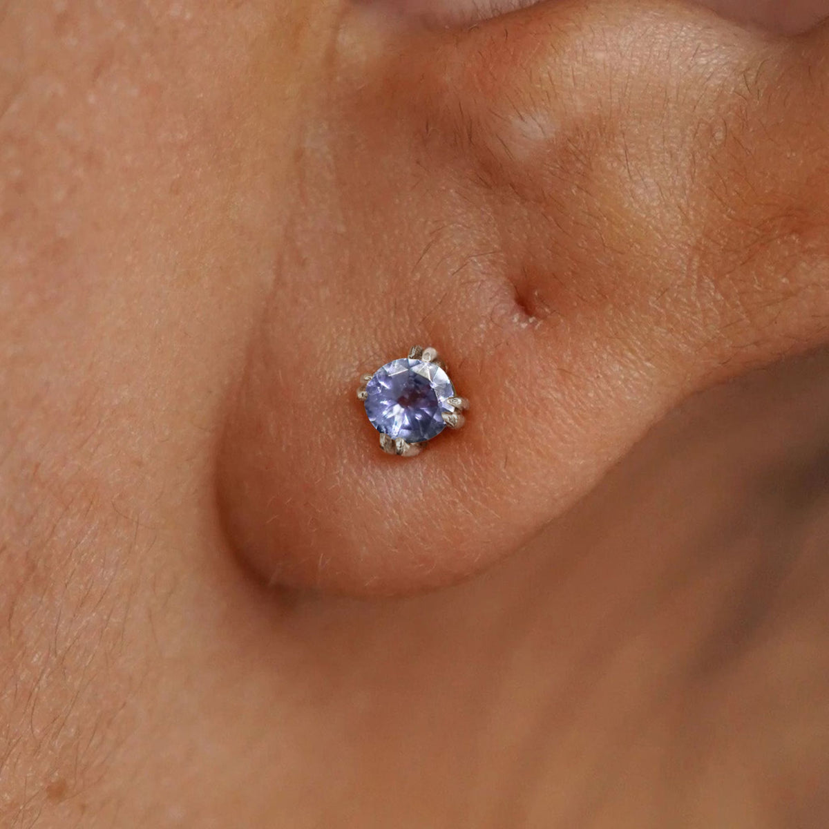Close up view of a model's ear wearing a 14k white gold Tanzanite Earring