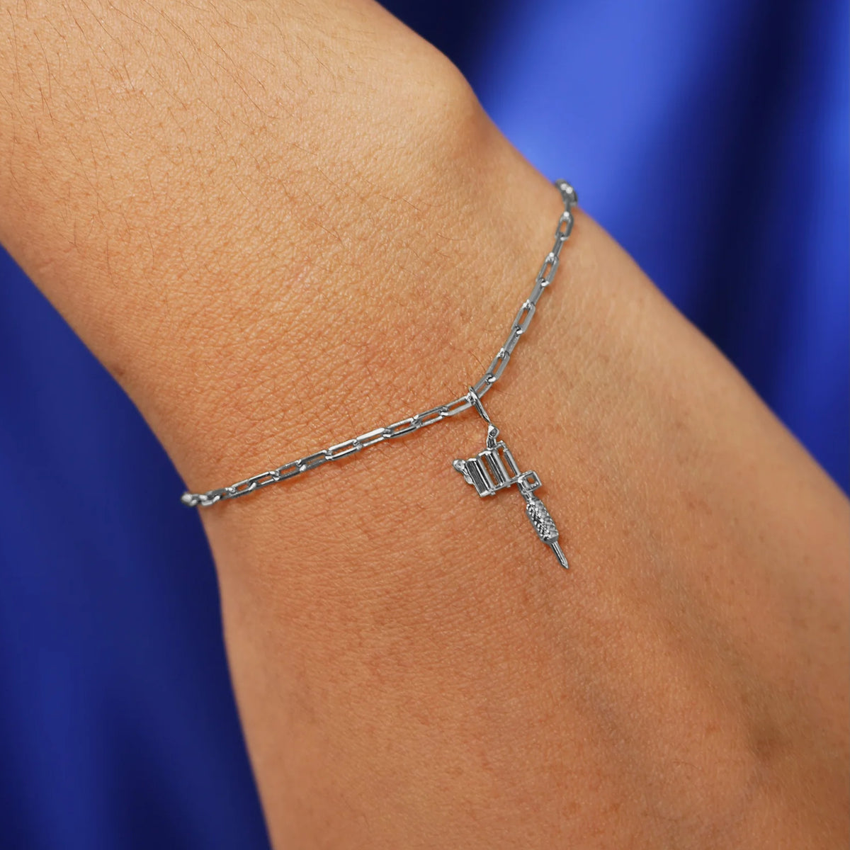 Close up view of a model's wrist wearing a white gold Tattoo Machine Charm on a Butch Bracelet
