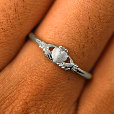 Close up view of a model's fingers wearing a 14k white gold Thin Claddagh Ring
