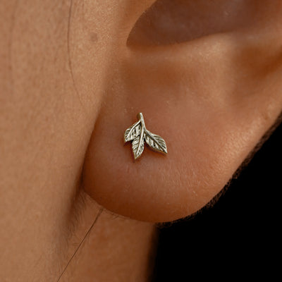 Close up view of a model's ear wearing a 14k white gold 3 Leaves Earring