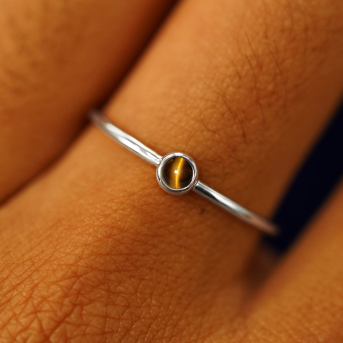 Close up view of a model's fingers wearing a 14k white gold Tiger Eye Ring