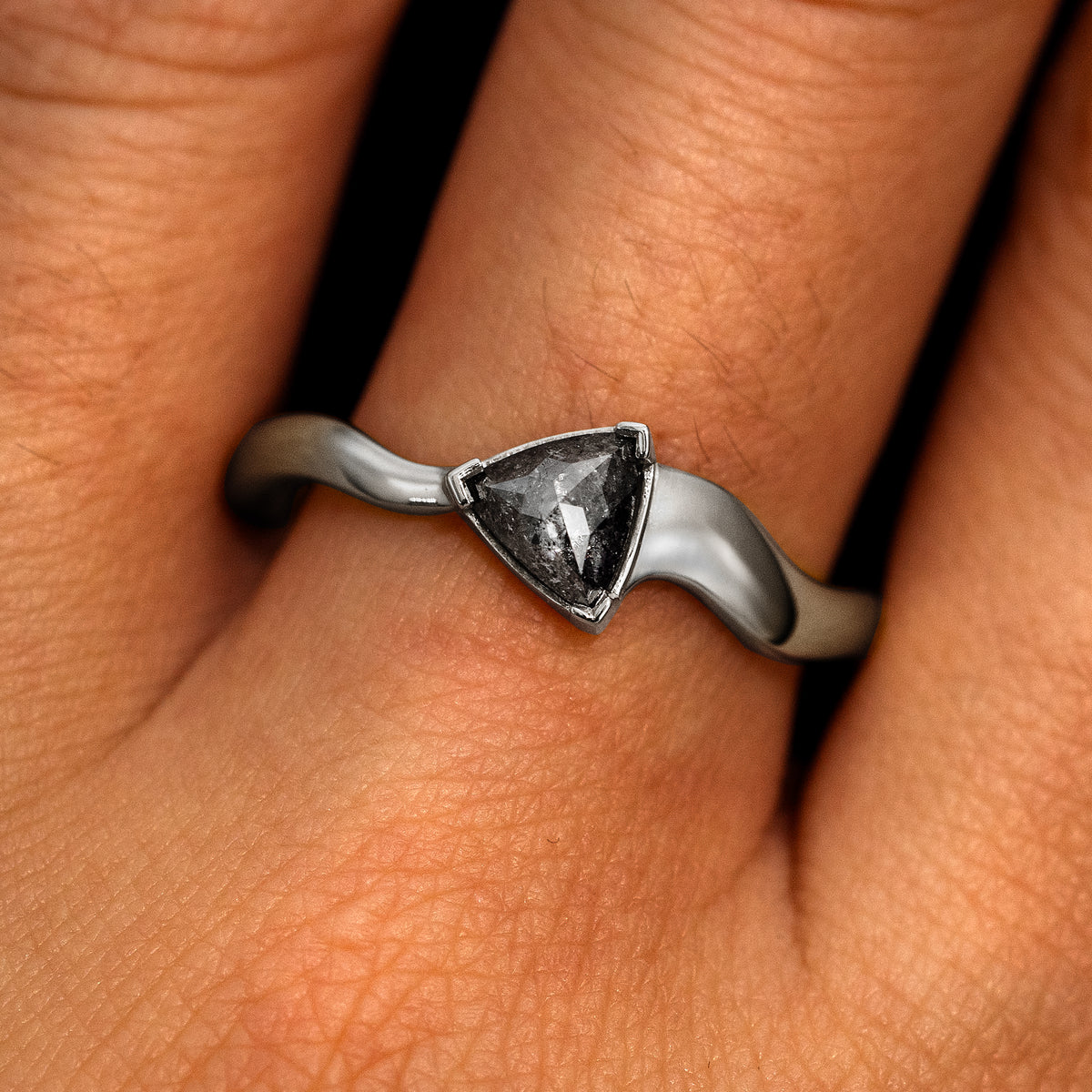 A model's hand wearing a 14k white gold Trillion Salt and Pepper Diamond Wavy Ring