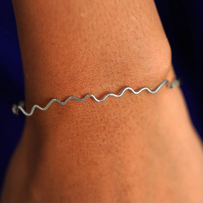 Close up view of a model's wrist wearing a 14k white gold Wave Bangle Bracelet