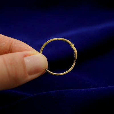A model holding a 14k gold Diamond Bird Wings Ring upright to show the thickness of the band