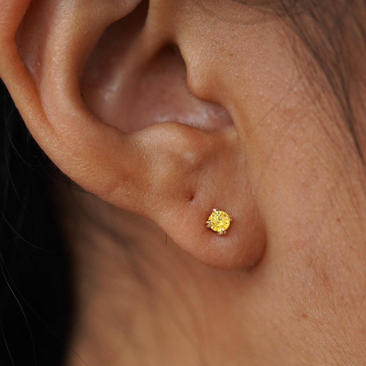 Close up view of a model's ear wearing a yellow gold Yellow Diamond Flat Back Earring