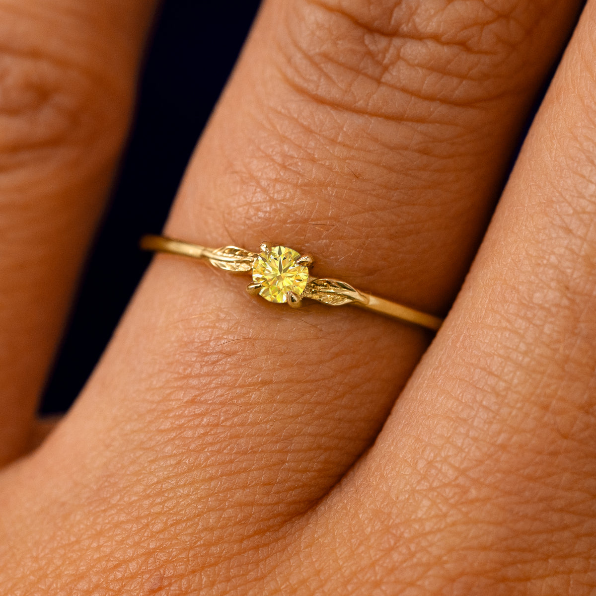 A solid 14k yellow gold Yellow Diamond Two Leaf Ring on a model's finger