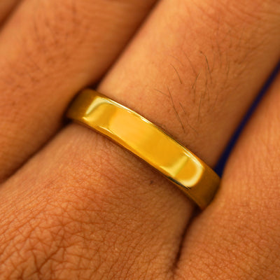 Close up view of a model's fingers wearing a 24k Band with a mirror finish