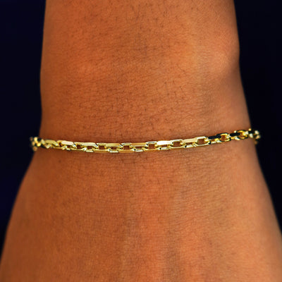 A model's wrist wearing a solid 14k yellow gold Anchor Bracelet