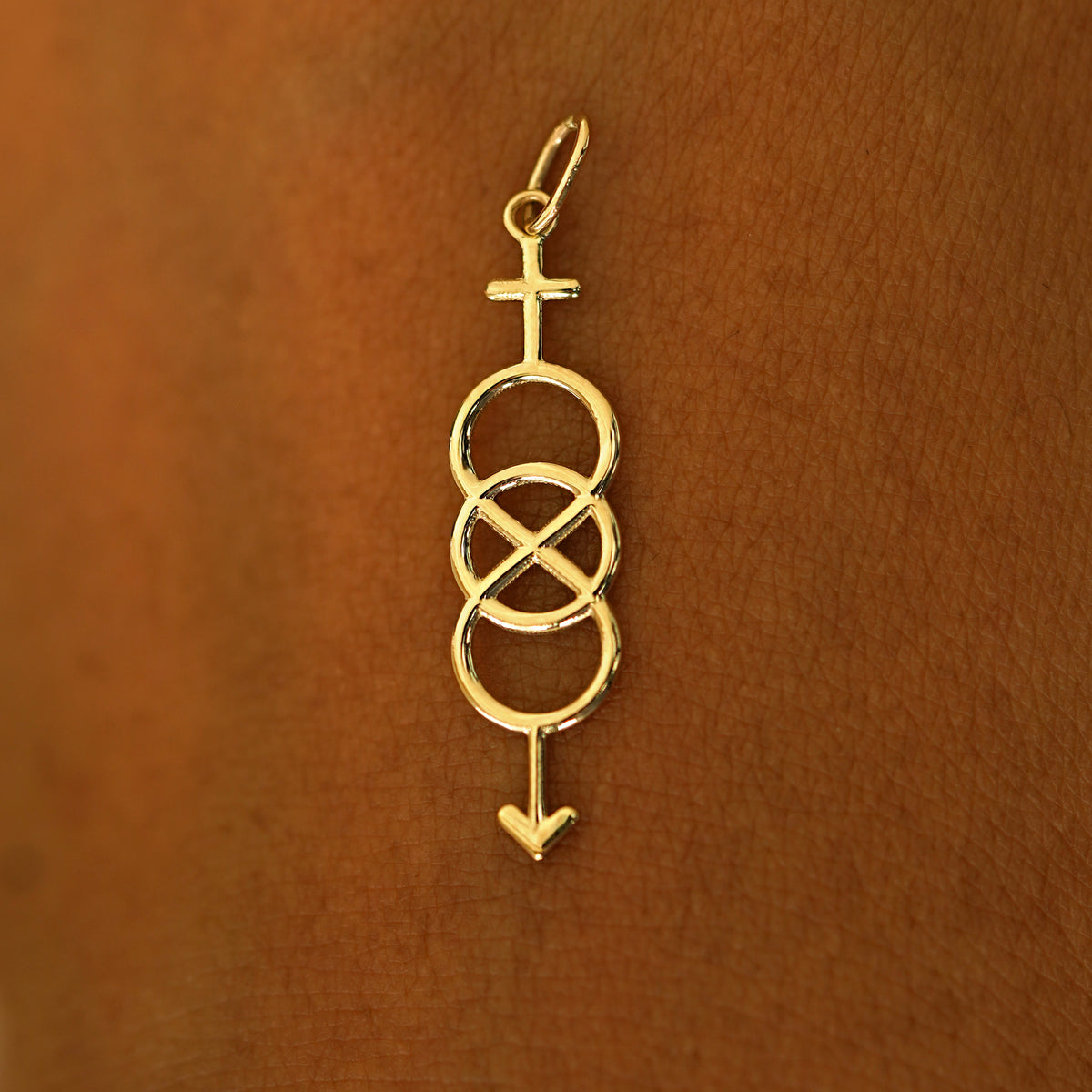 A solid 14k yellow gold Bisexual Symbol Charm resting on the back of a model's hand