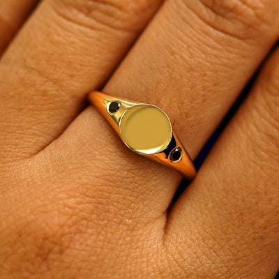 Close up view of a model's fingers wearing a 14k yellow gold Black Diamond Signet Ring