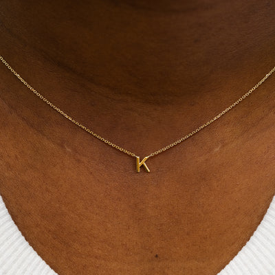 Close up view of a model's neck wearing a 14k solid yellow gold Block Initial Necklace in the letter K