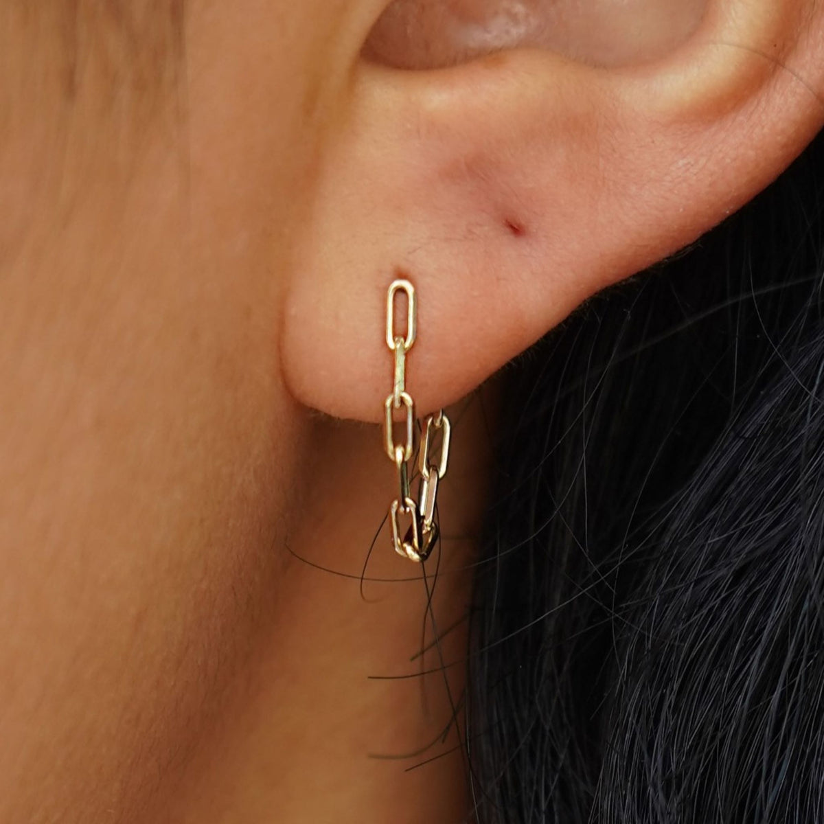 A model's ear wearing a yellow gold Butch Chain Loop Earring