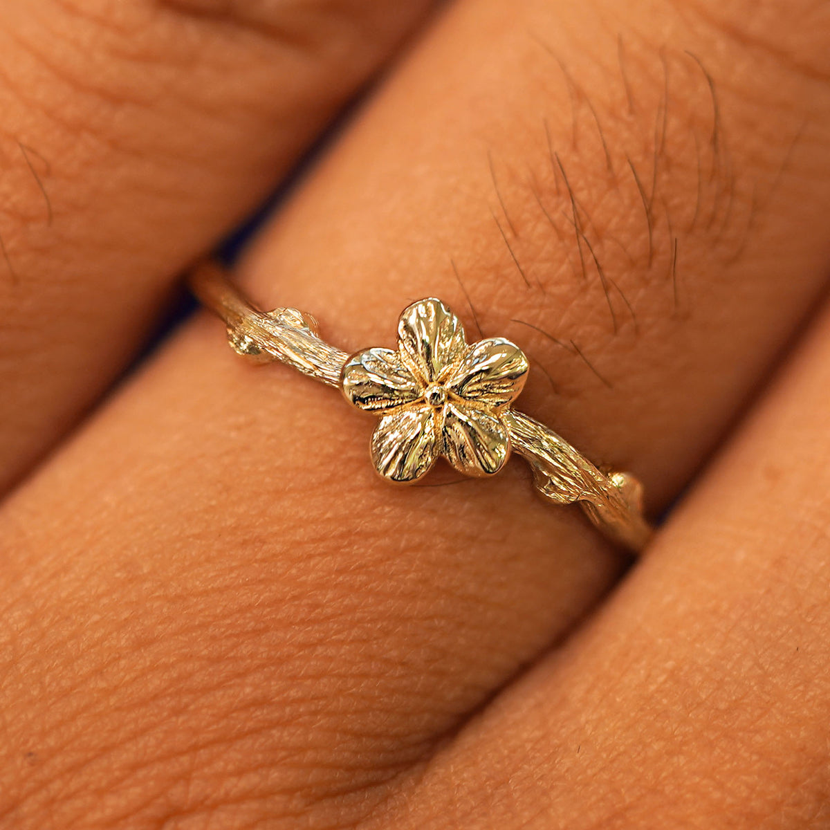 Close up view of a model's fingers wearing a yellow gold Sakura Ring