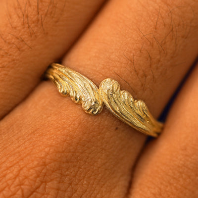 Close up view of a model's fingers wearing a 14k yellow gold Crashing Waves Band