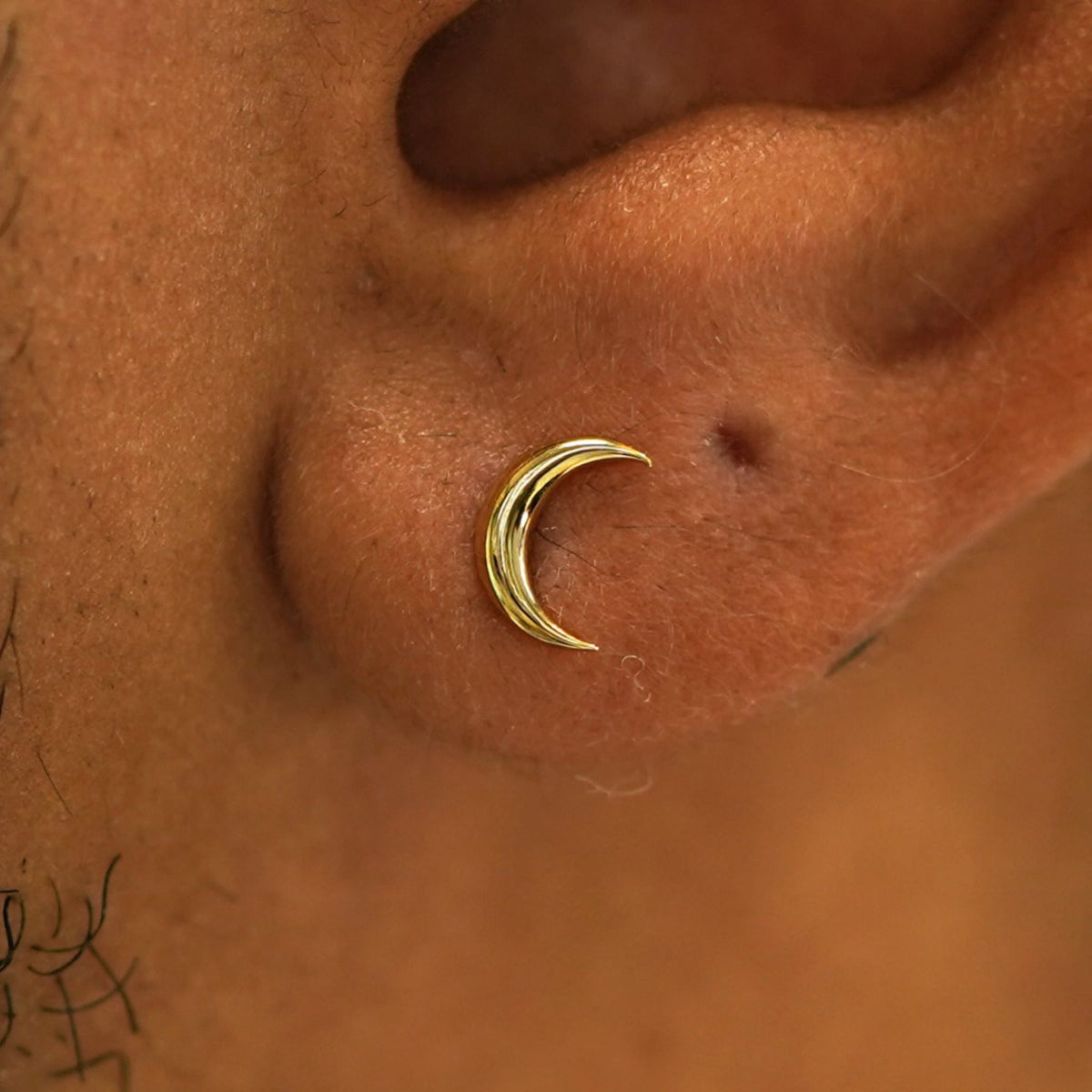 Close up view of a model's ear wearing a 14k yellow gold Moon Earring