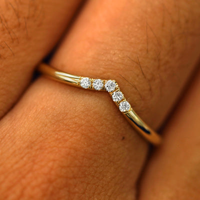 Close up view of a model's fingers wearing a 14k yellow gold Diamond Chevron Band