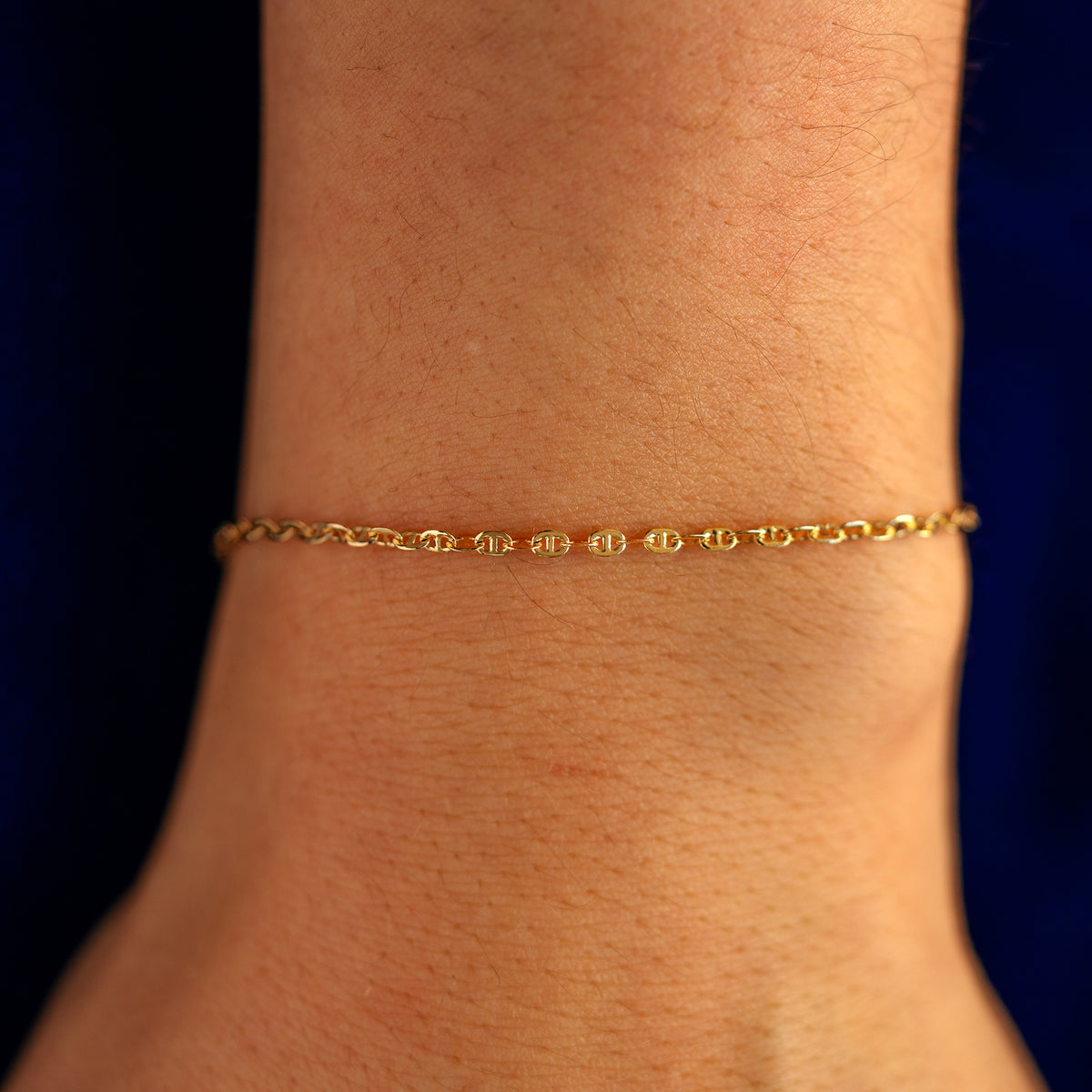 Close up view of a models wrist wearing a solid 14k yellow gold Flat Mariner Chain Bracelet