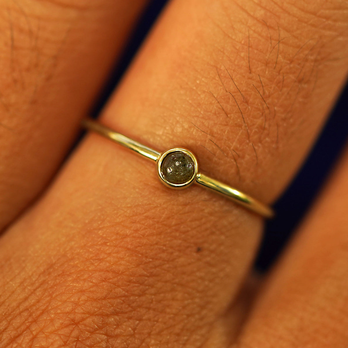 Close up view of a model's fingers wearing a 14k yellow gold Labradorite Ring