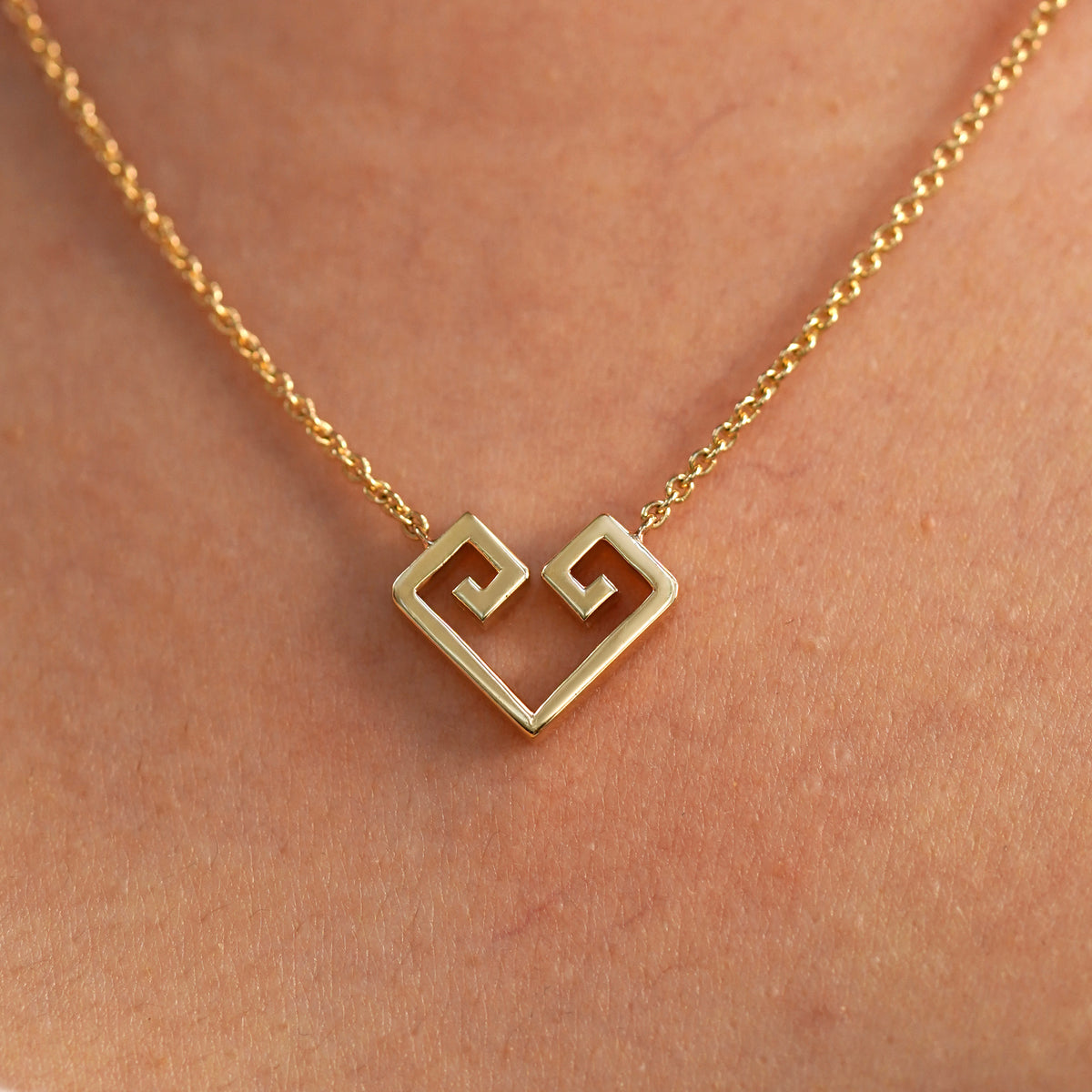 A close up view of a model's neck wearing a yellow gold Large Chere Heart Necklace